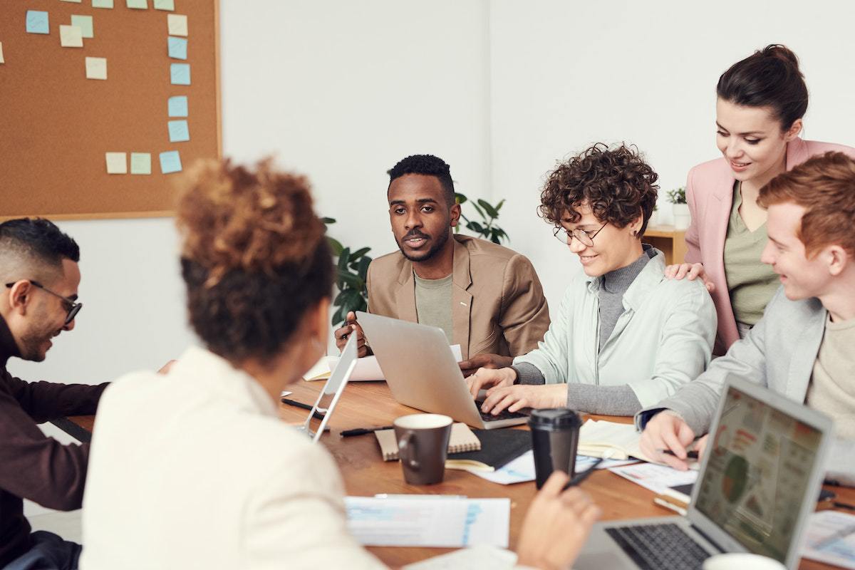 Diversidade e inclusão na empresa representados por equipe com homens e mulheres reunidos ao redor de mesa bolando estratégia