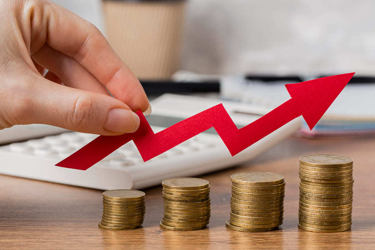 Lucro: Fusão de empresas Pessoa segurando símbolo de gráfico em ascensão sobre moedas mostrando lucro pós Fusão de empresas