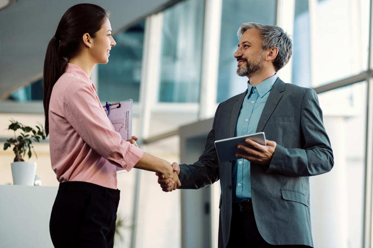 Acordo: Fusão de empresas Homem e mulher em escritório se cumprimentando e fazendo acordo para Fusão de empresas