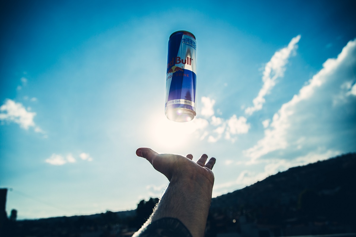 Pessoa com mão erguida para o céu enquanto aparentemente recebe lata de Red Bull, empresa que faz uso do Live marketing