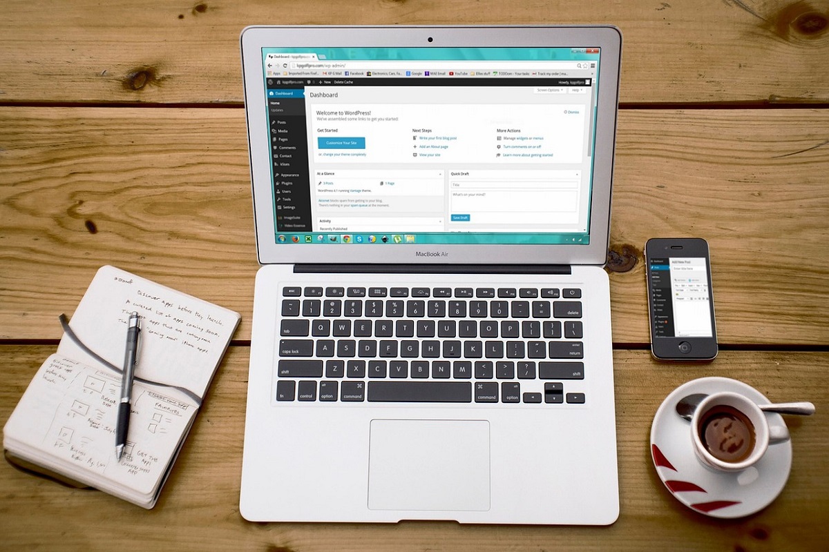 Notebook sobre mesa de madeira e ao lado de xícara de café e agenda em tela inicial do WordPress em Mobile friendly