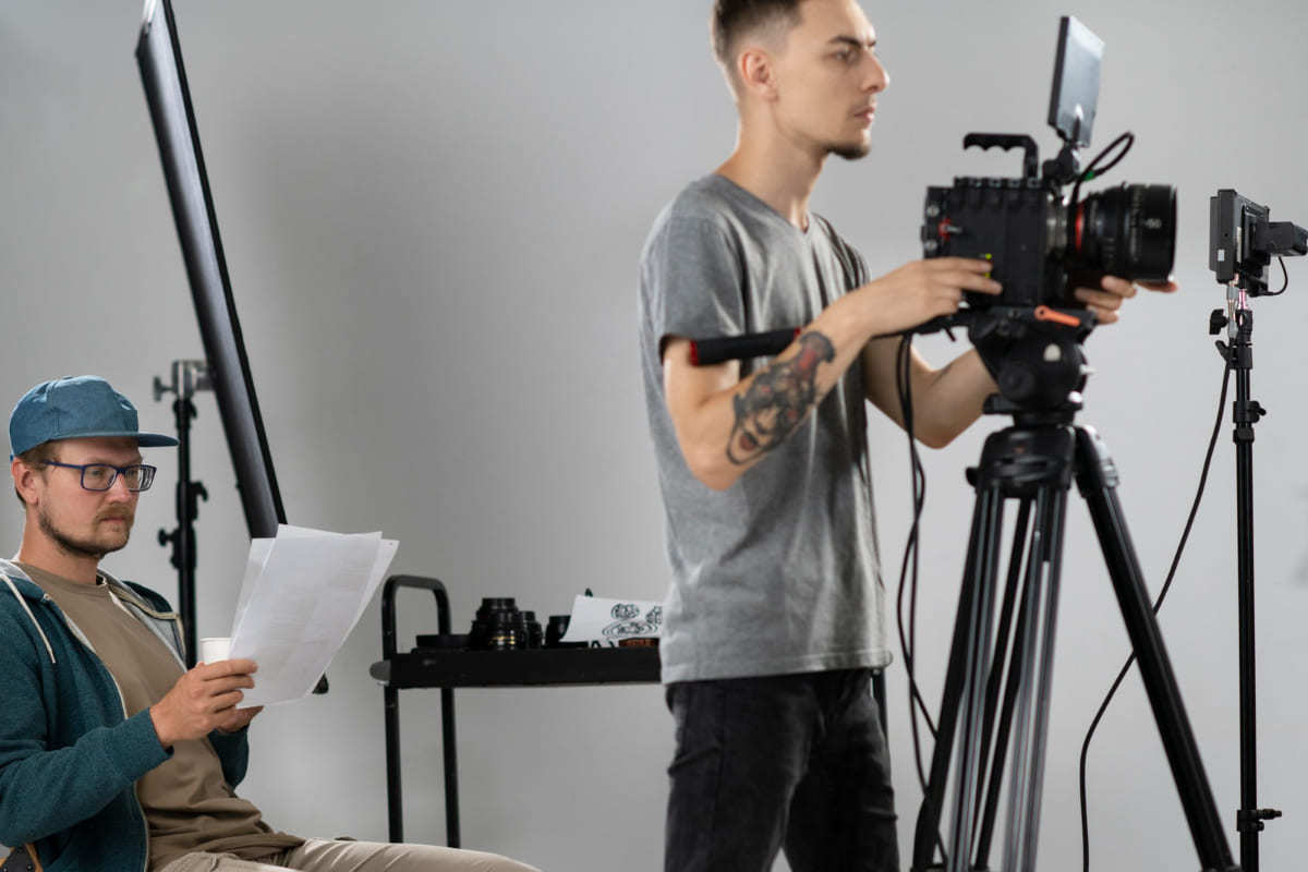 Gravação: Product placement Homem sentado lendo folhas com roteiro de gravação com câmera man à sua frente em estúdio