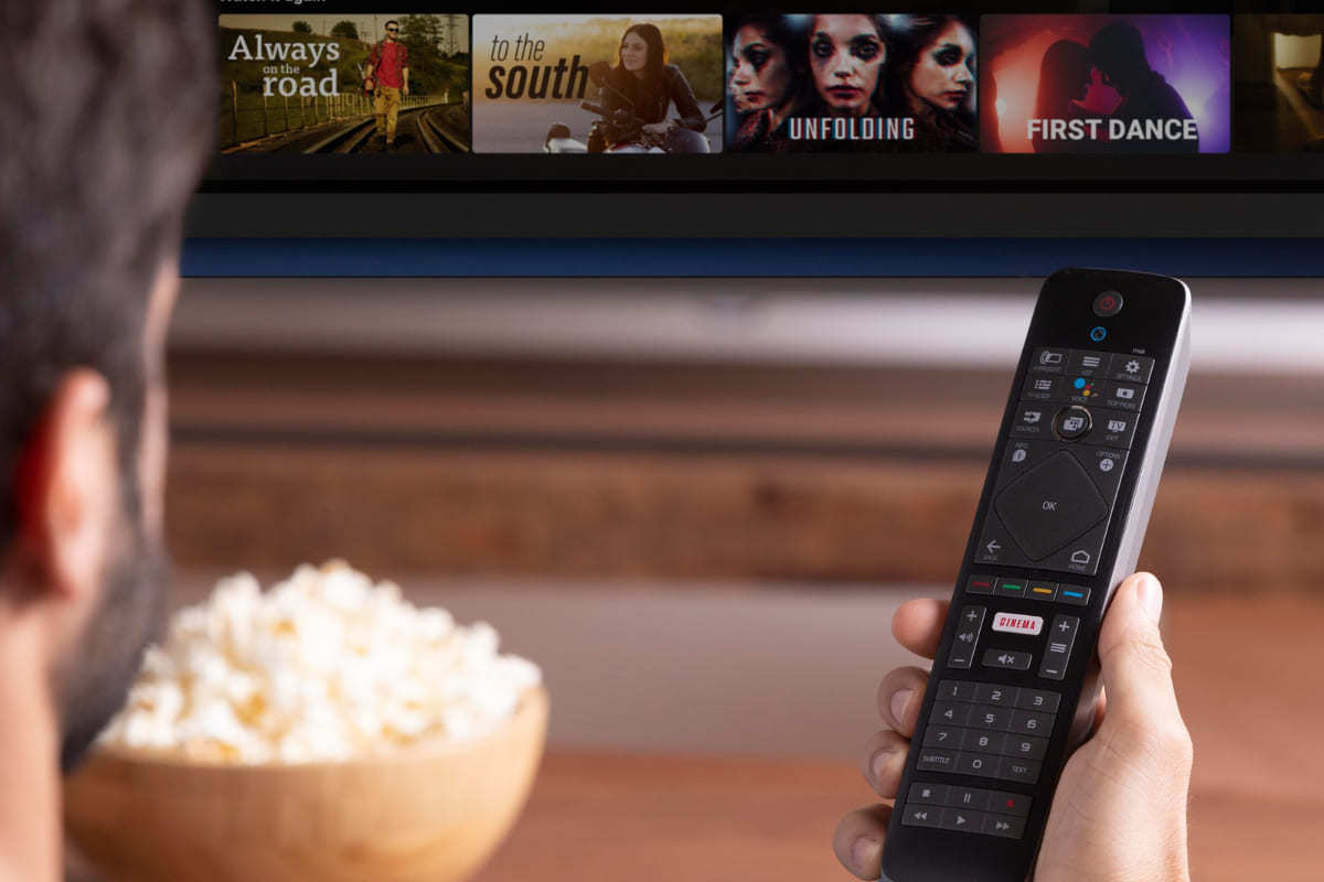 Assistir: Product placement Homem segurando bowl com pipoca e controle de SMART TV sentado em sofá para assistir