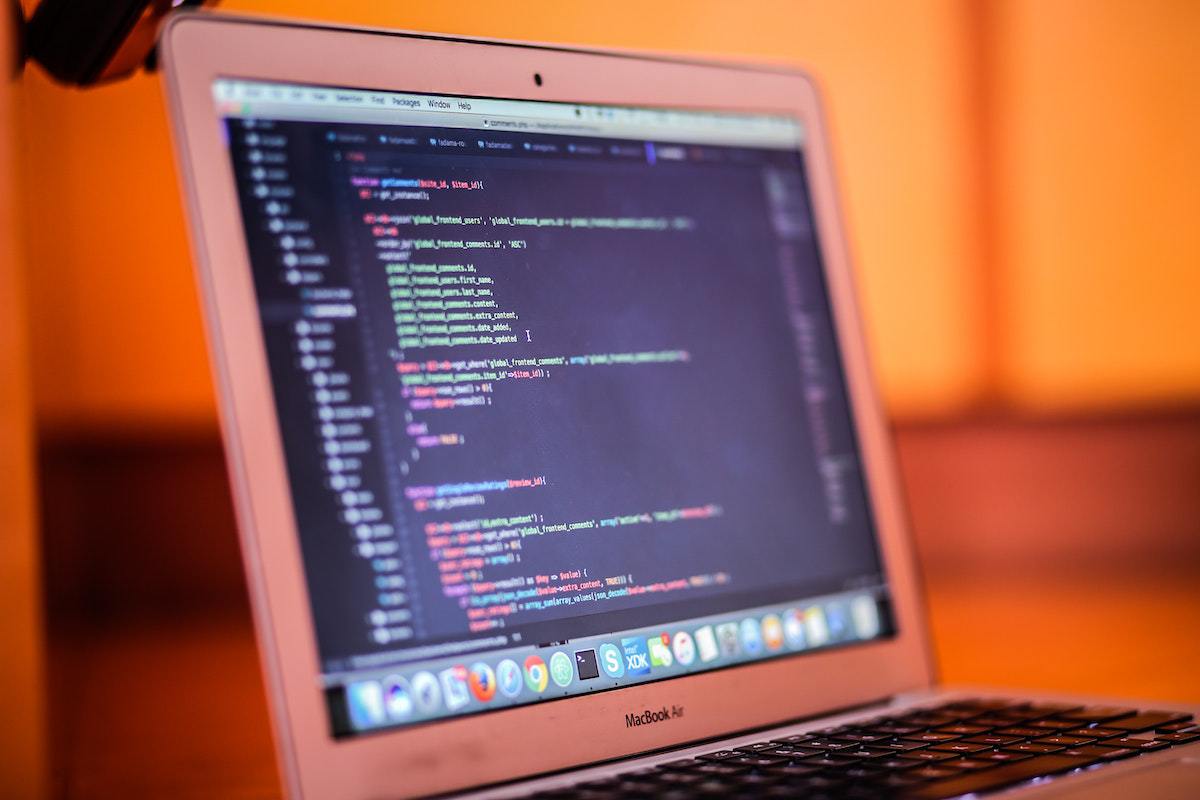 Pessoa fazendo análise e desenvolvimento de sistemas programando código em notebook