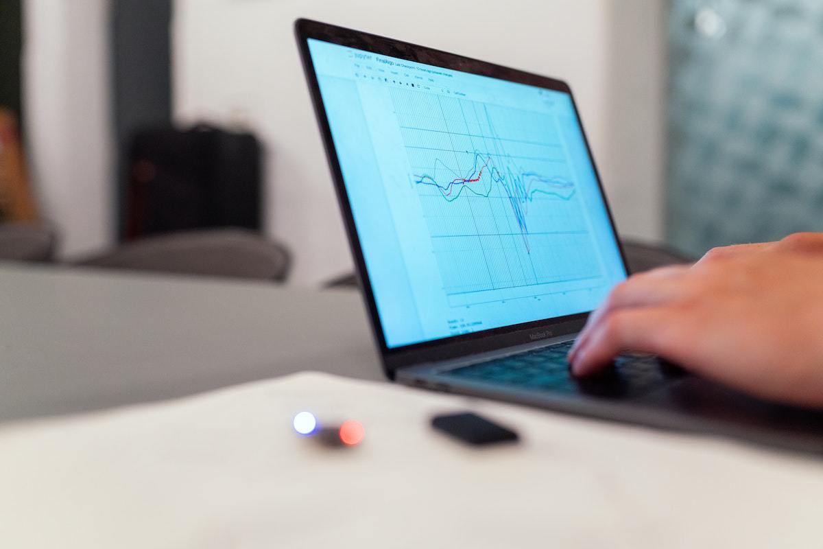 Pessoa usando notebook para analisar gráficos em sua tela sobre mesa cinza