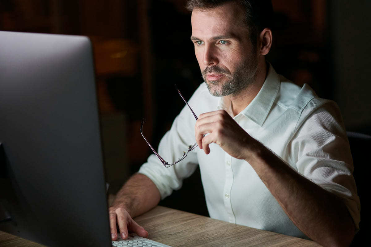 Computador: Psicologia do consumo no e-commerce Homem usando computador sobre mesa de madeira com grande monitor