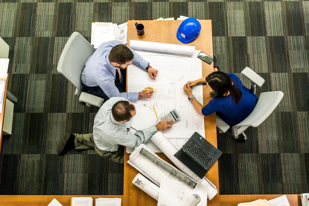 Pessoas em escritório sentados ao redor de mesa analisando dados com Sales manager