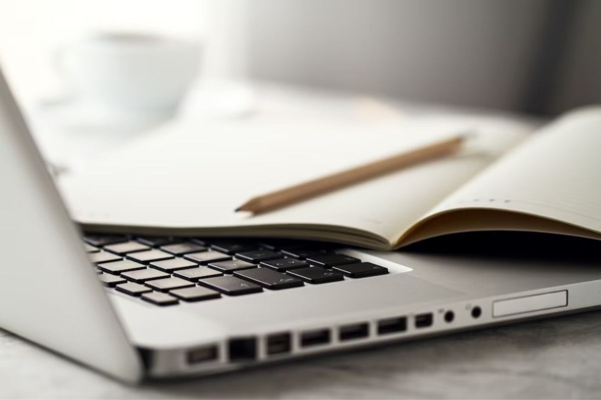 Revista sobre teclado de notebook com lápis sobre o mesmo