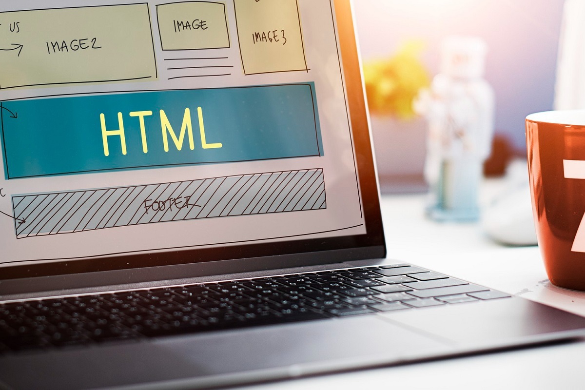 HTML: WordPress multisite Notebook sobre mesa de madeira com tela exibindo esboço de layout para site que poderá usar as vantagens do WordPress multisite, onde o mesmo já apresenta espaço para imagens e conteúdo, onde neste consta a sigla HTML
