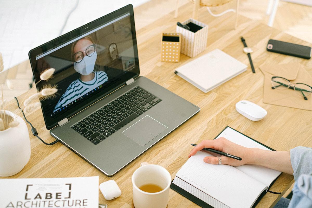 pessoa trabalhando em seu laptop e fazendo anotações