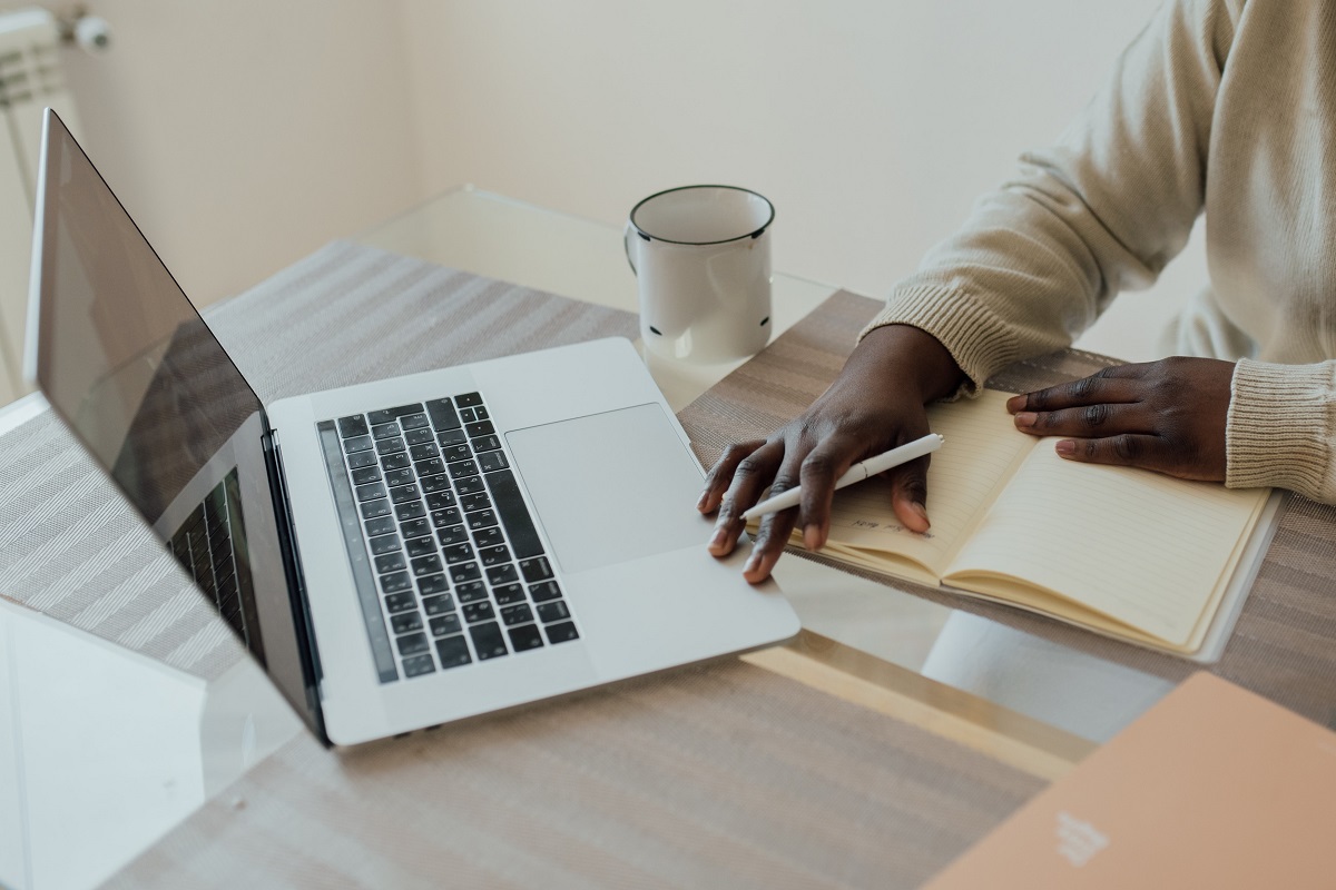 Escritório: Veículos para enviar release Pessoa em escritório fazendo planejamento de Veículos para enviar release usando notebook sobre mesa de madeira