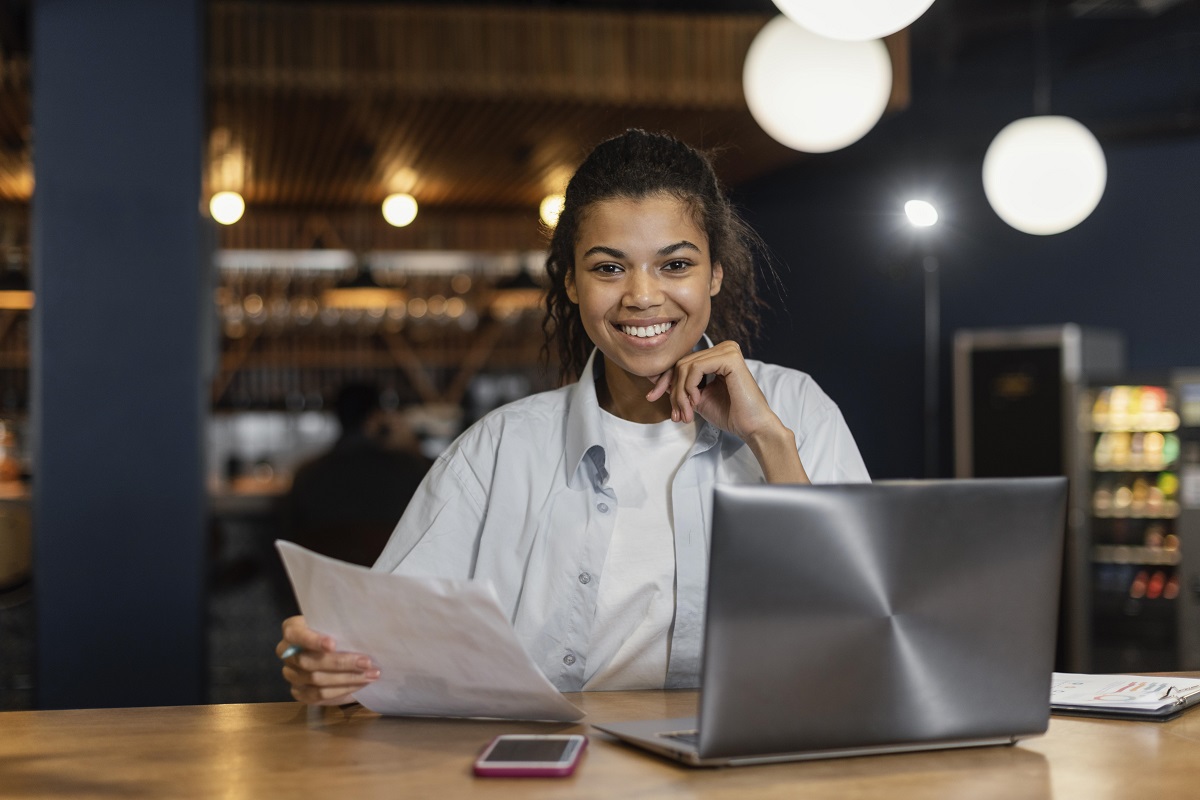 mulher sorrindo: empreendedor mulher sorrindo e com um laptop à sua frente