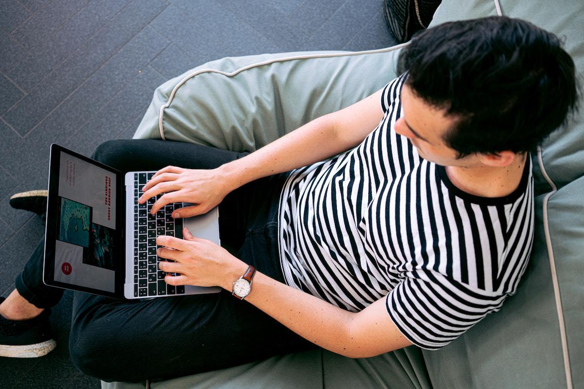 homem sentado em sofá usando o laptop