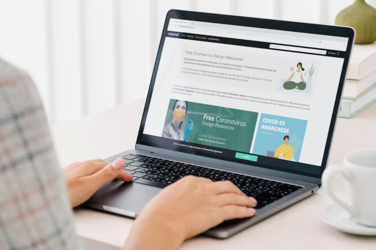 O fim dos cookies de terceiros e o futuro do marketing digital Pessoa usando um laptop para acessar recursos de design gratuitos sobre o coronavírus em um site, com uma xícara de café ao lado.