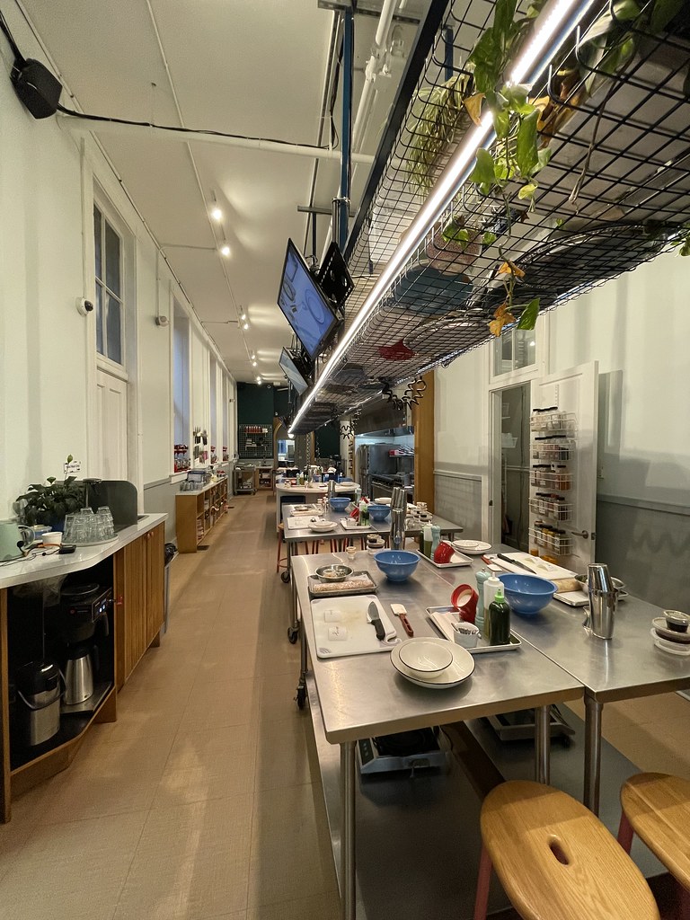A large, open space full of stainless steel counters and cooking equipment. The room goes pretty far back. Each table is set up the same, so that everyone has all the same ingredients and equipment at their station.