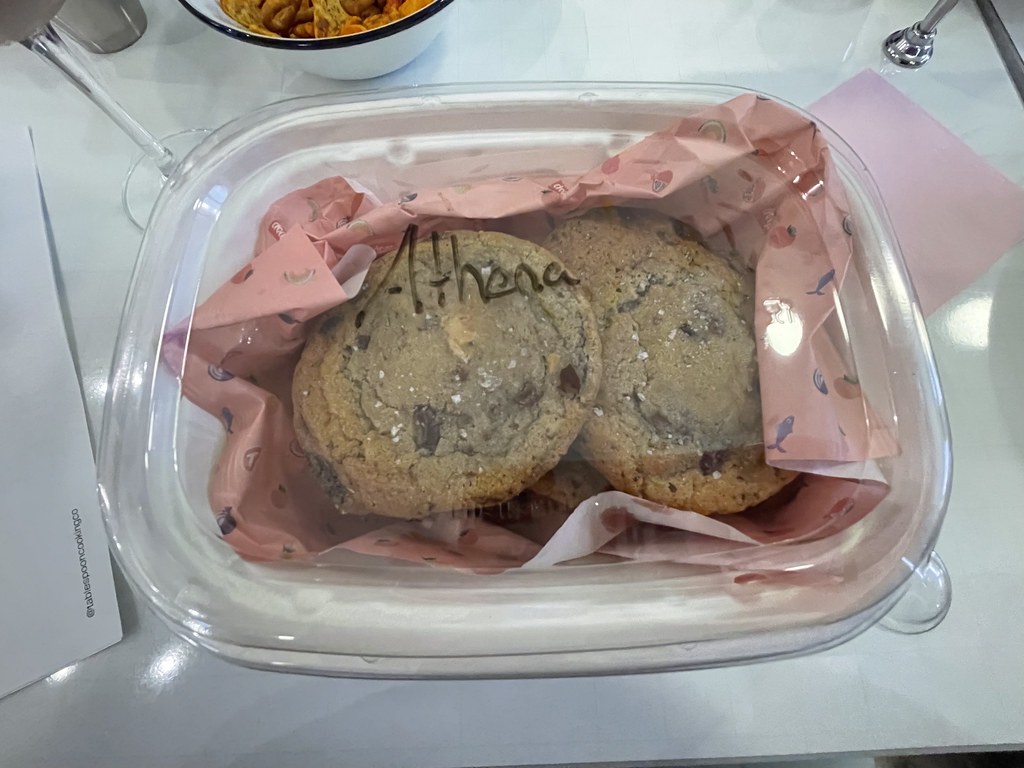 A medium sized container of cookies with pink tissue paper and my name written on the container. 