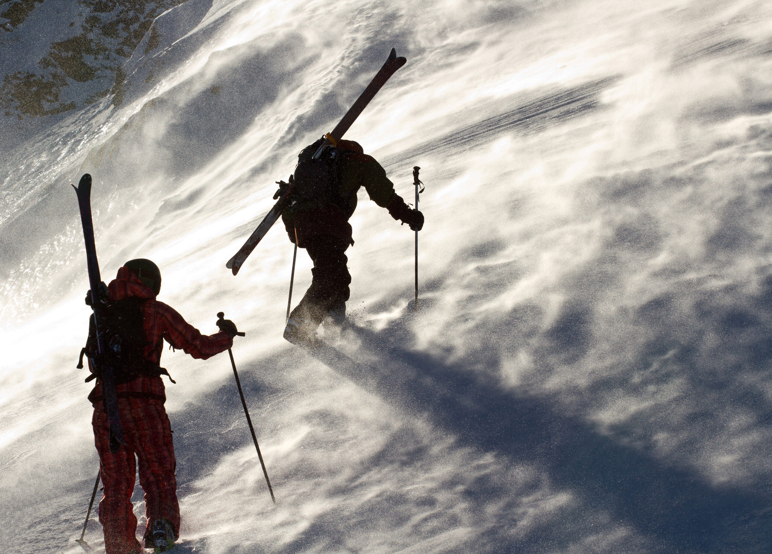 Two skiers on a windswept ski slope