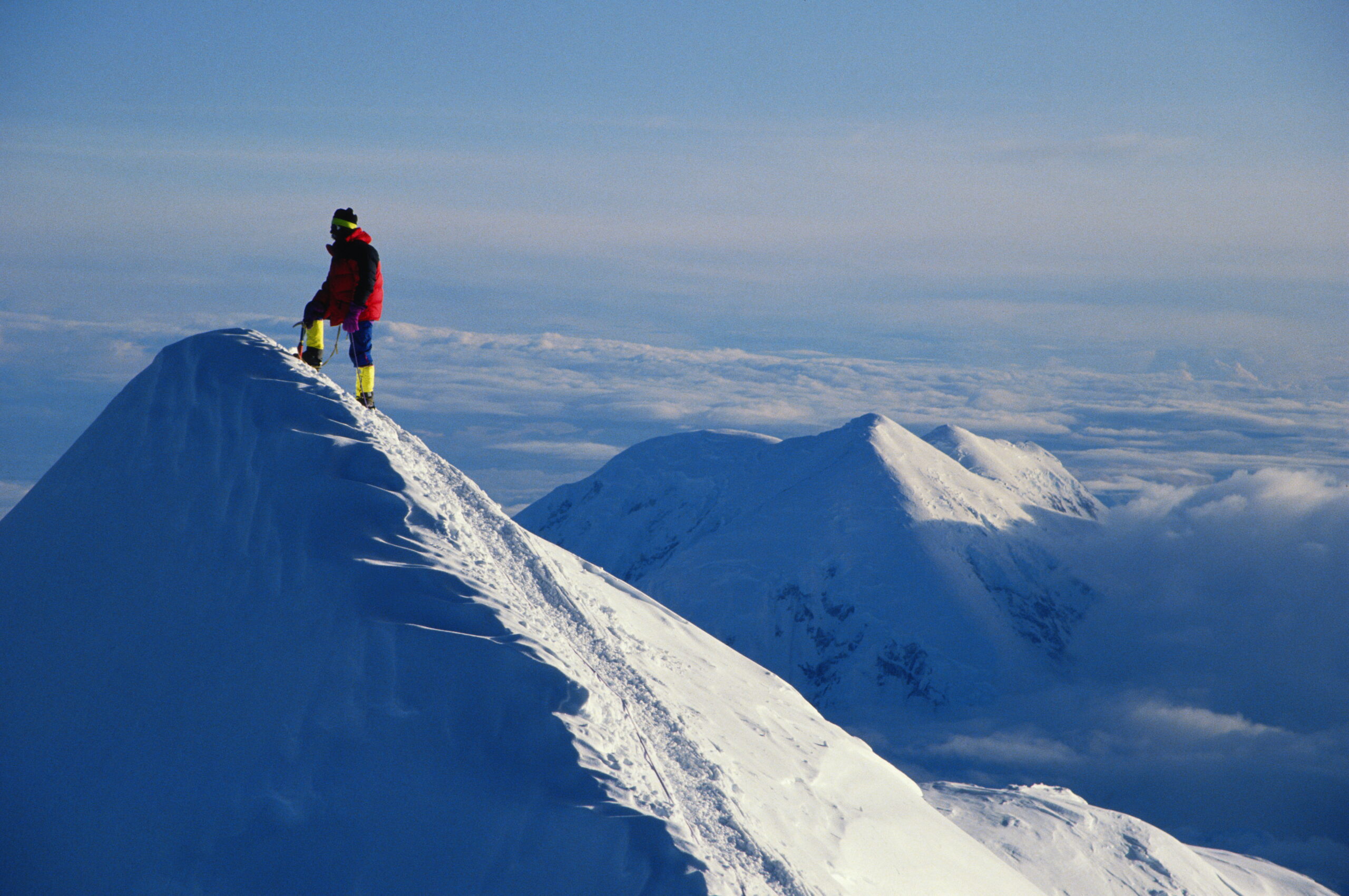 A mountain climber on the summit of a snowy peak
