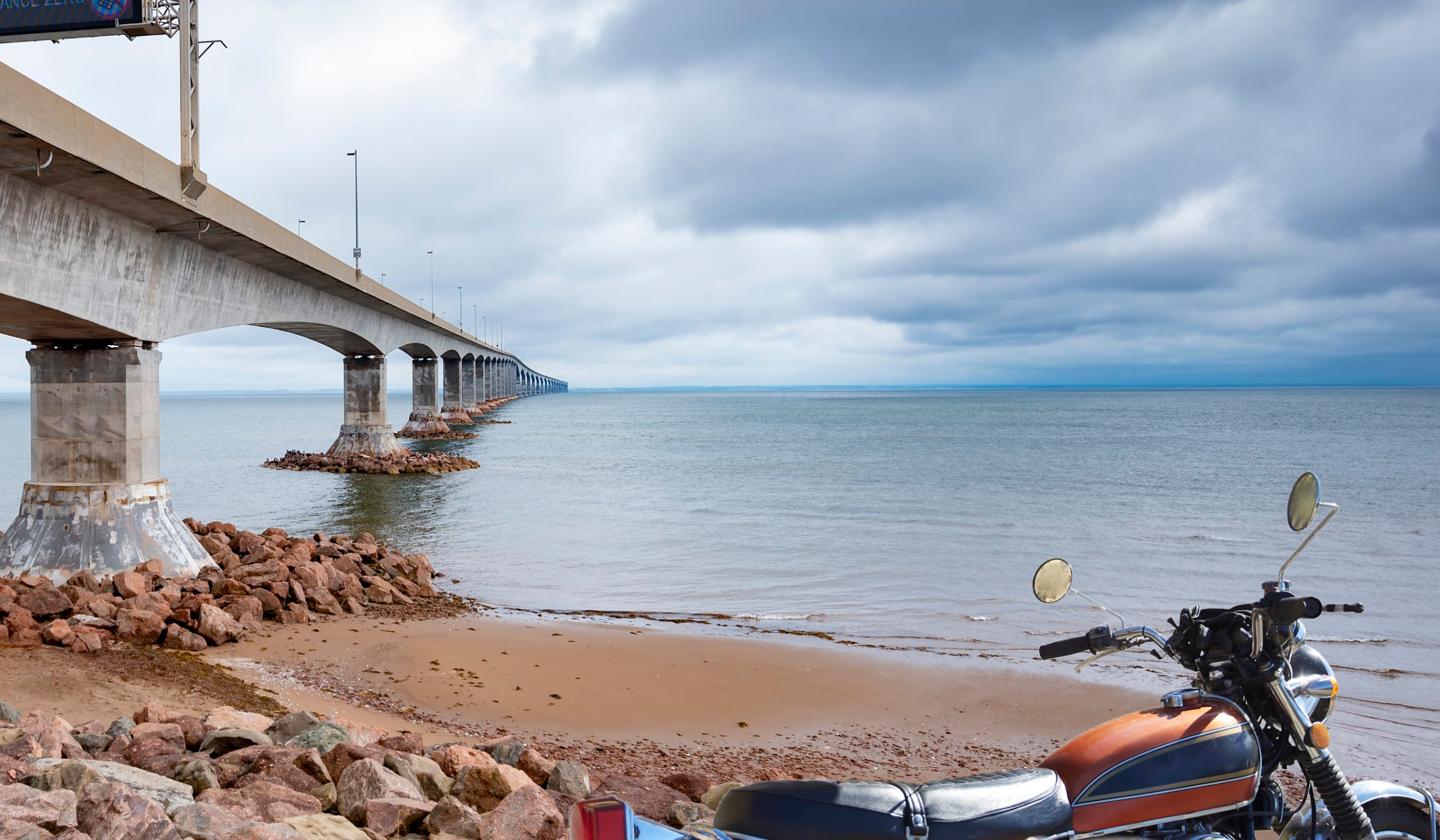 A motorcyle stands on the shore near the Confederation Bridge which spans the distance between New Brunswick and Prince Edward Island, Canada.