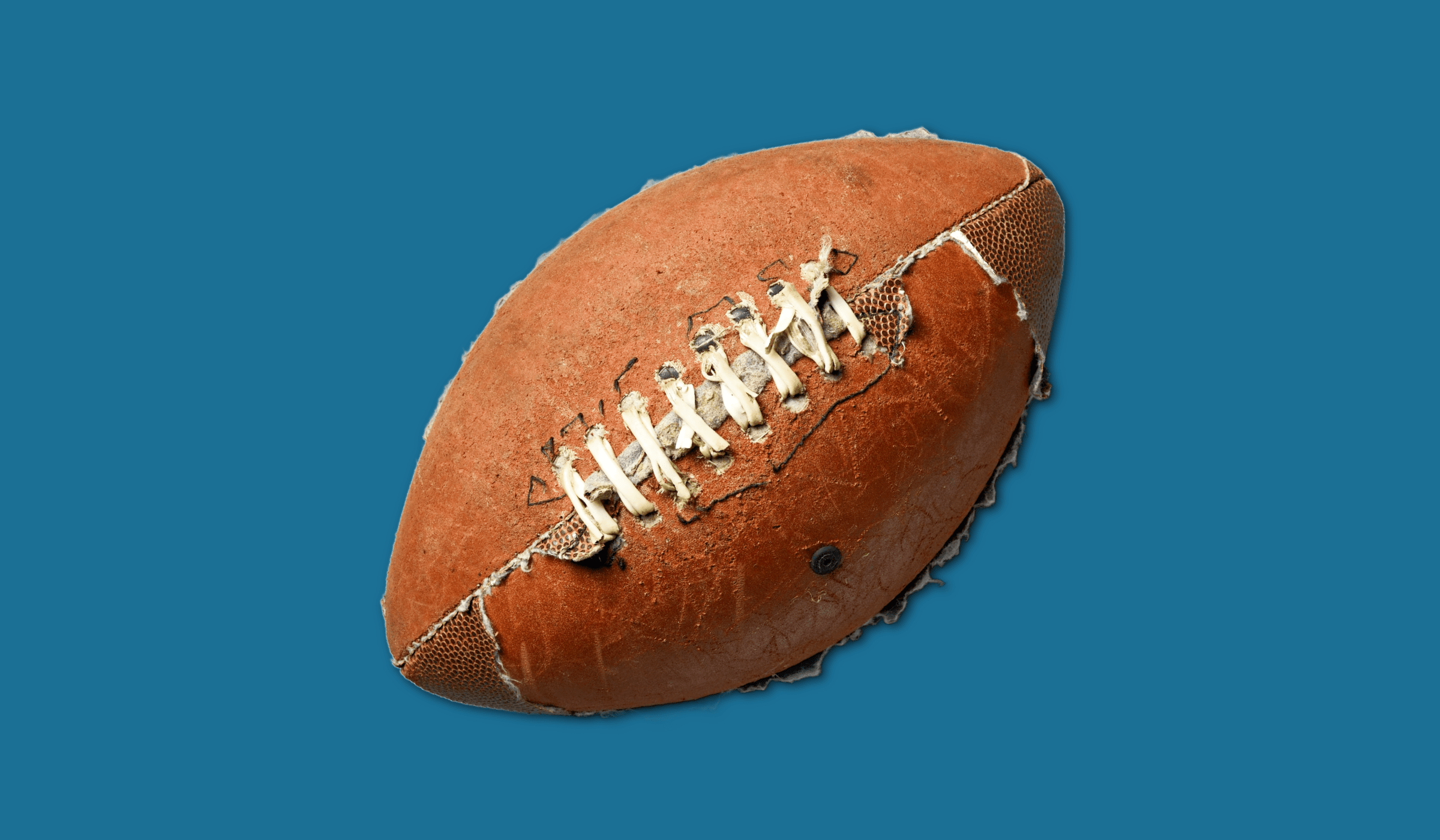 A very worn football on a blue background.