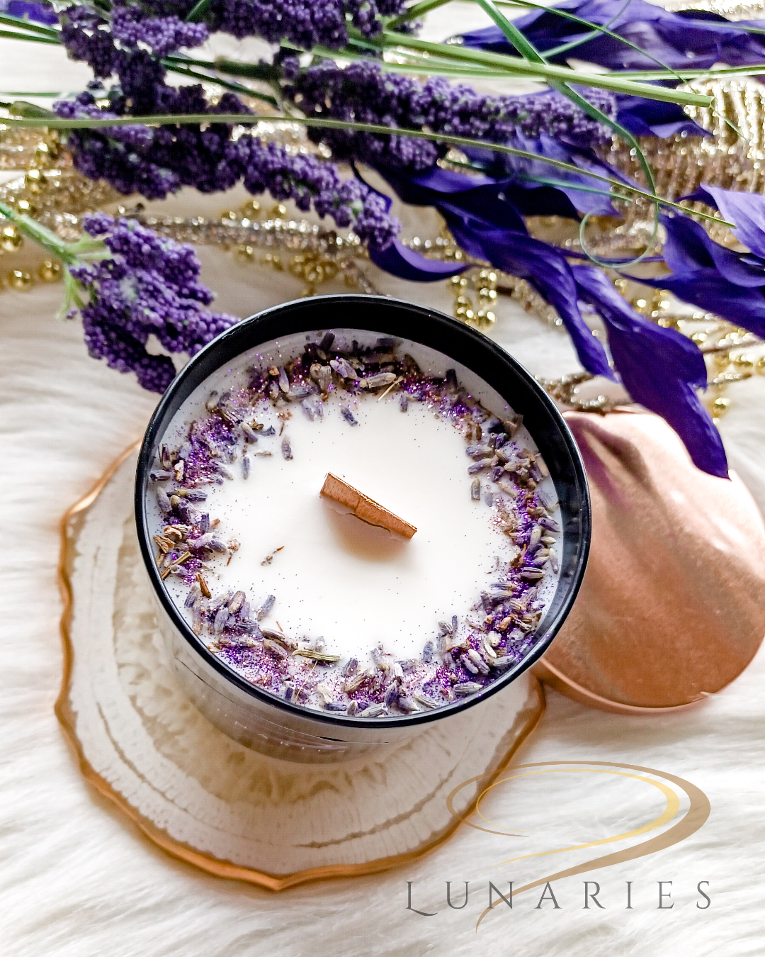 Lavender Fields soy candle in a black glossy tumbler jar, featuring a wooden wick and decorated with real dried lavender buds and soft purple botanicals.