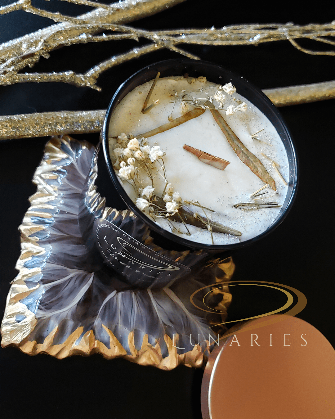 Vanilla Orchid soy candle in a black glossy tumbler jar, featuring a wooden wick and decorated with warm-toned botanicals in creamy, buttery hues.