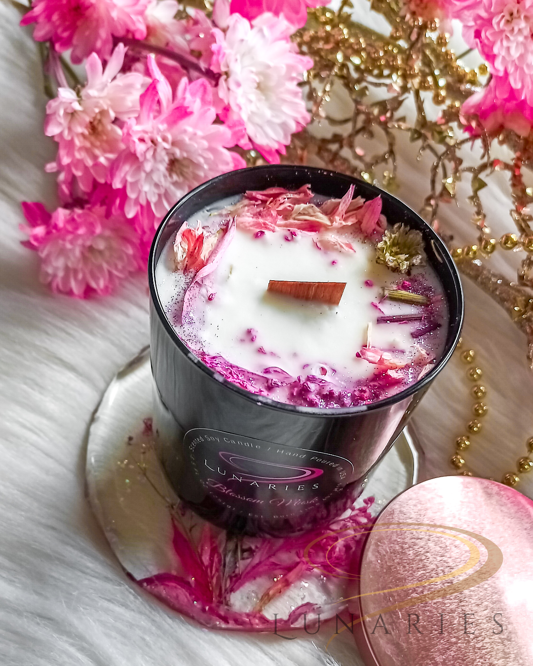 Blossom Musk soy candle in a black glossy tumbler jar, decorated with pink dried flowers and botanicals, featuring a wooden wick