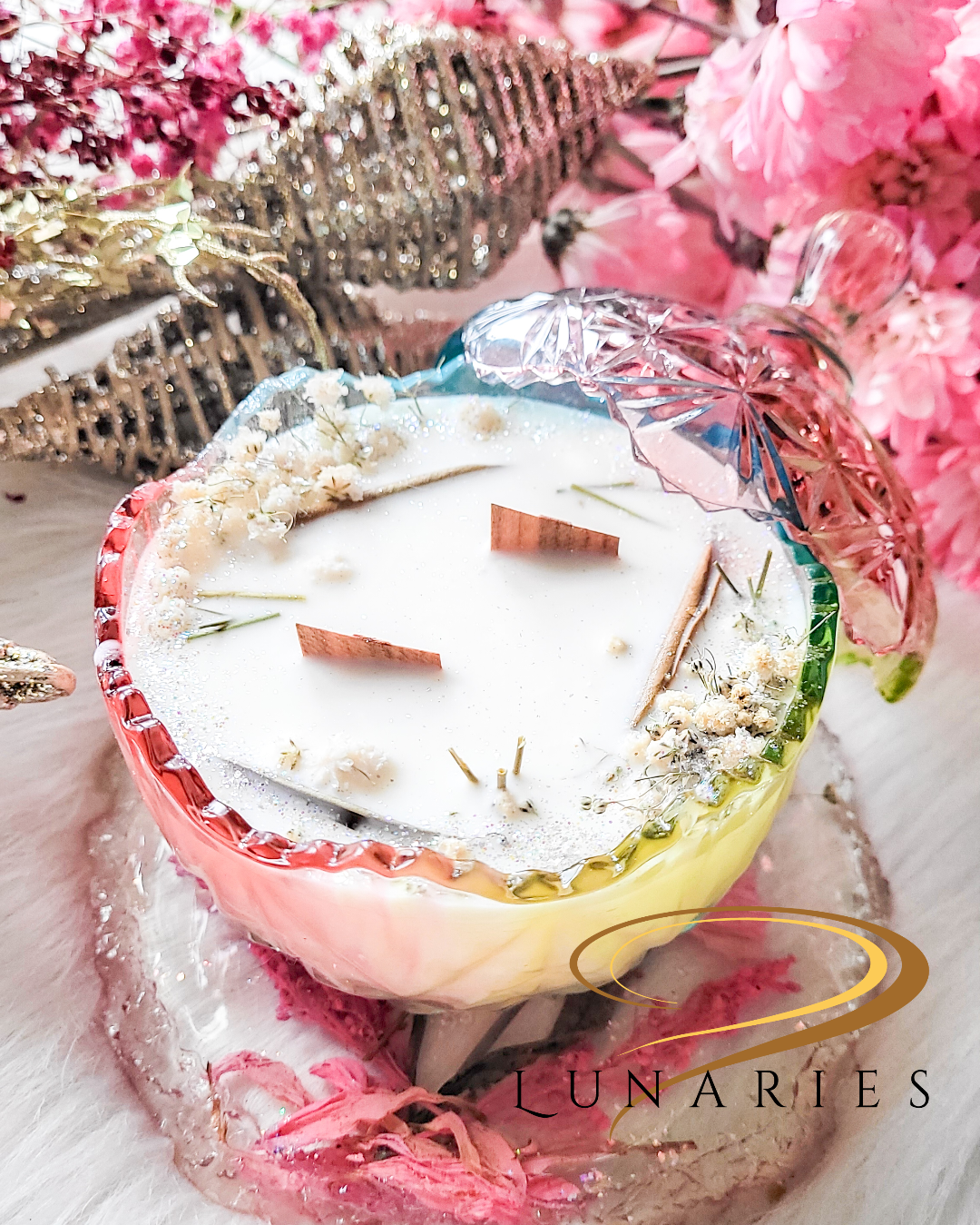 A soy wax candle with two wooden wicks, in a rainbow-colored, crystal-like glass jar, decorated with white and creamy botanicals.