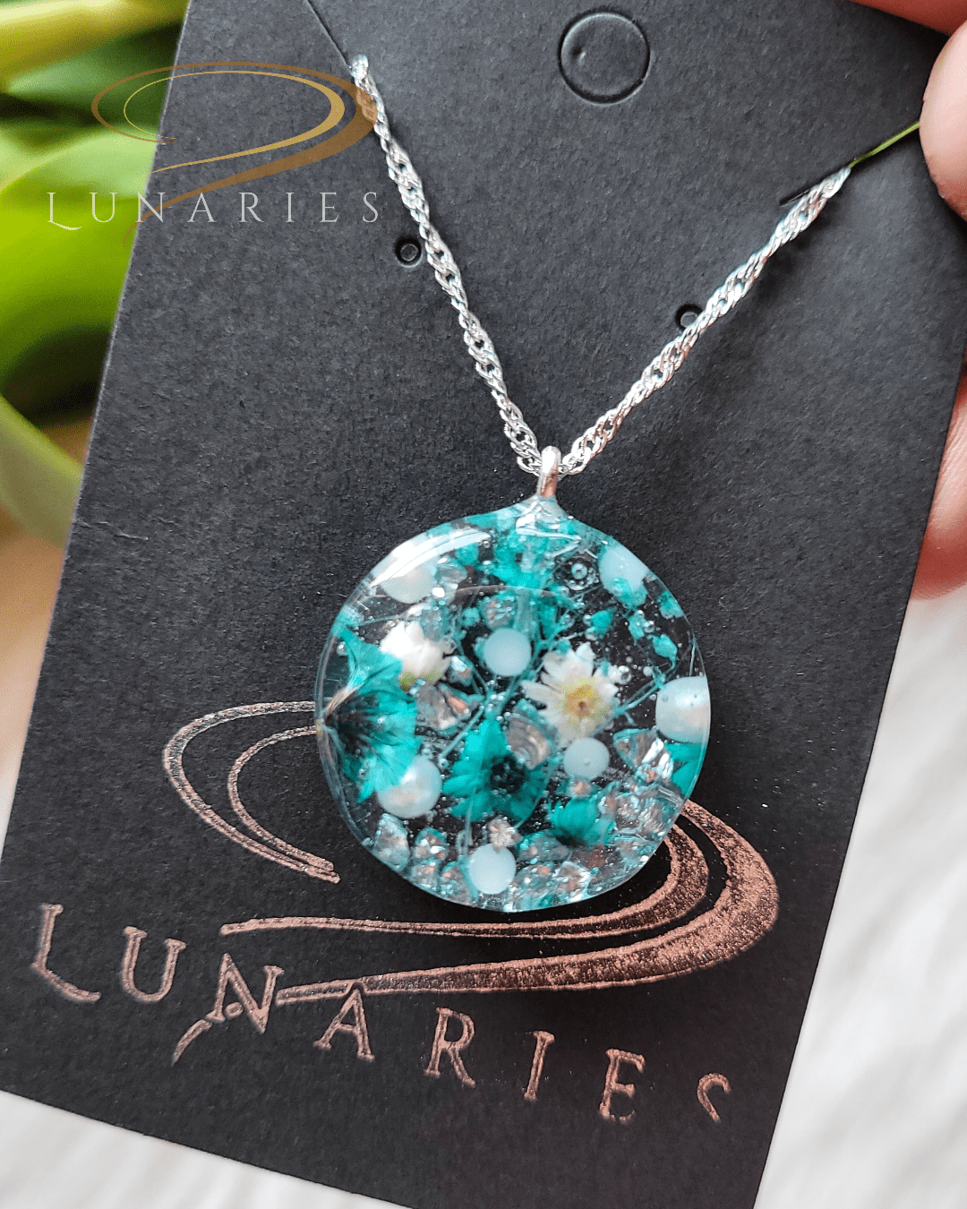 Round clear resin pendant with teal and white dried flowers