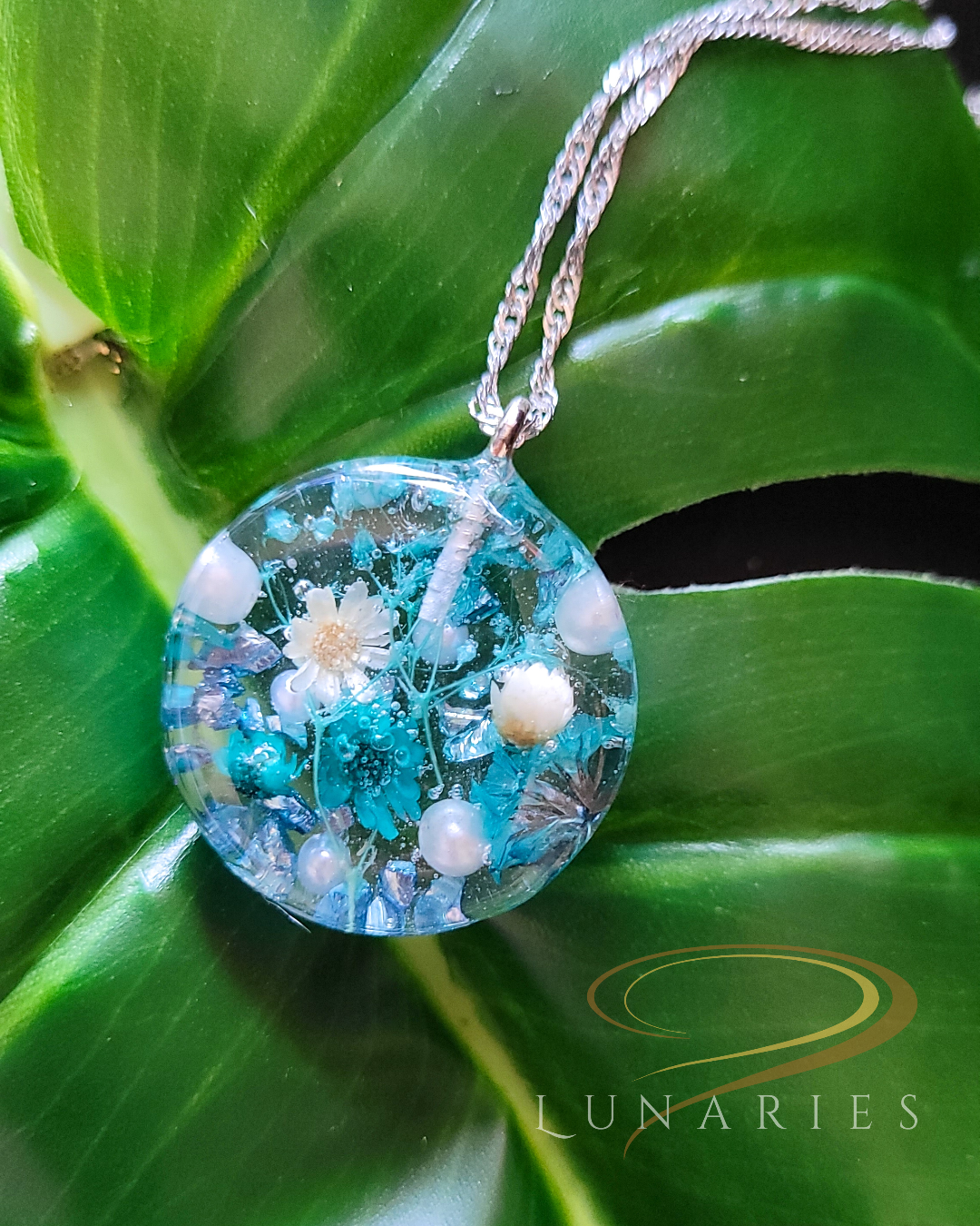clear resin pendant with teal dried flowers