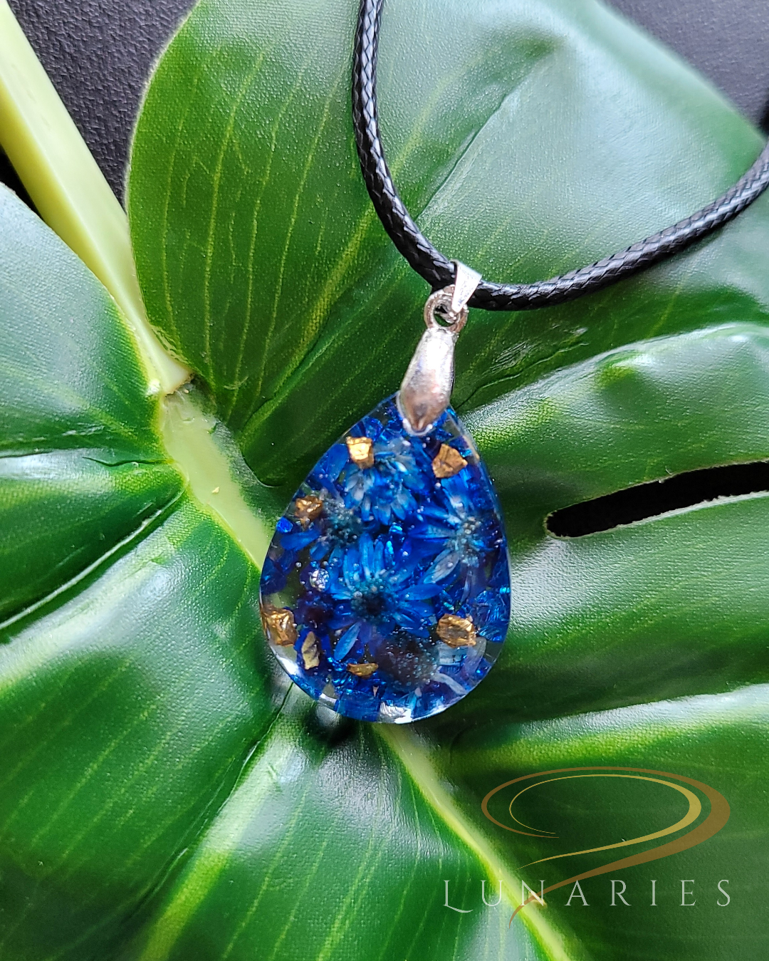 clear resin teardrop pendant with real dark blue dried flowers and tiny embellishments for refined look