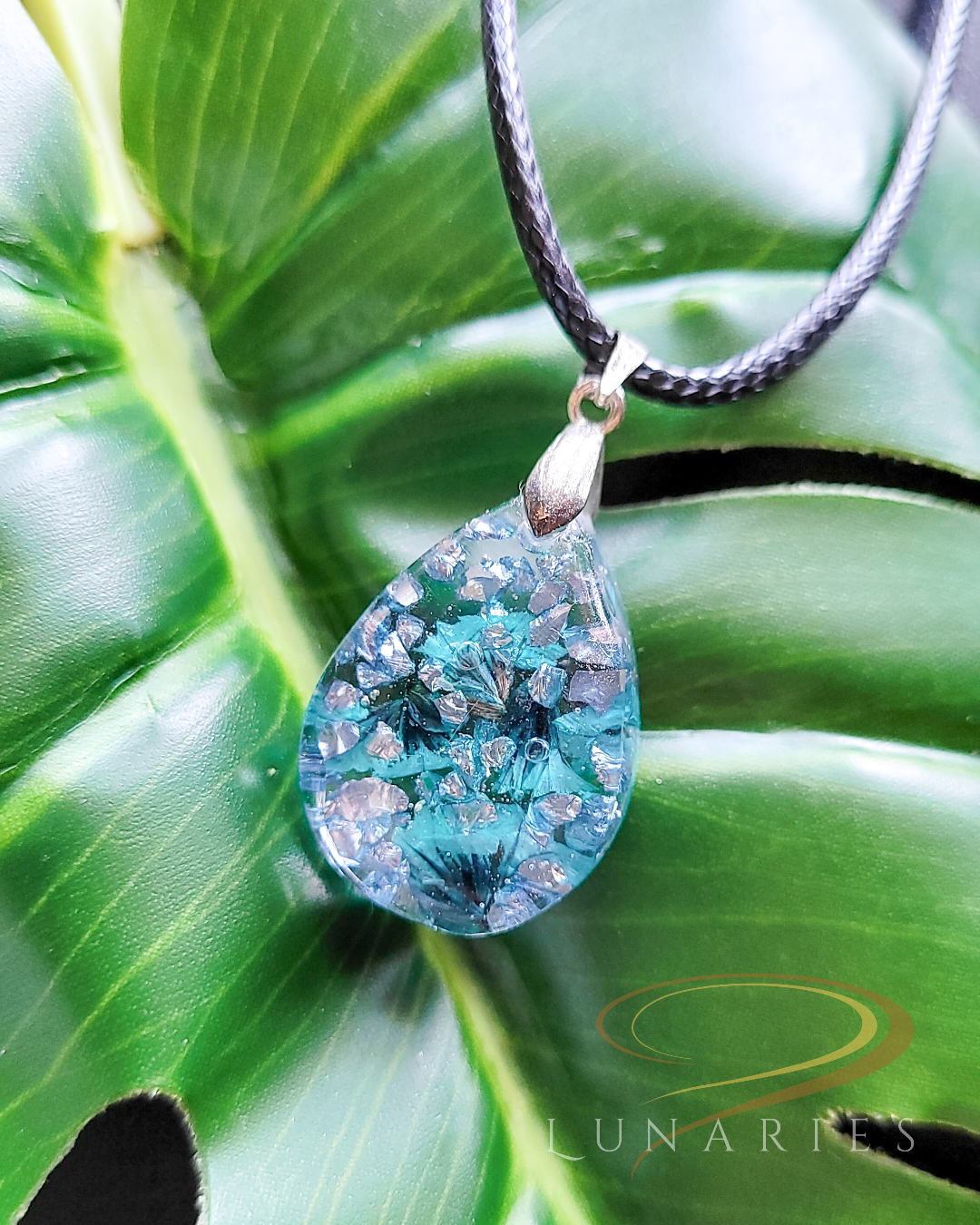 Clear resin teardrop pendant with real teal flowers and tiny teal embellishments