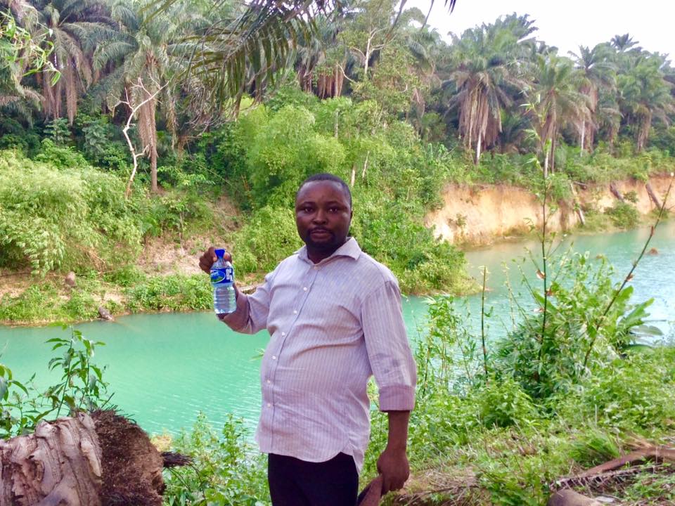 Thomas Thomas holds out a container to show that water from the river turns white when put inside a bottle [PHOTO CREDIT: Anietie Usen]