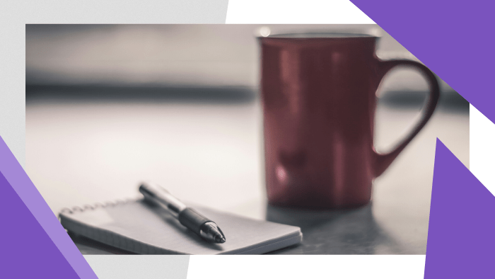 Pen and notepad next to a coffee mug