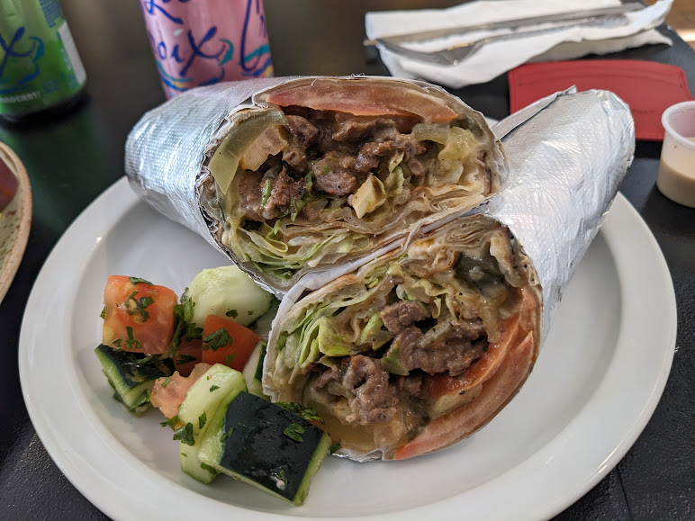 A burrito with meat and vegetables on a plate.