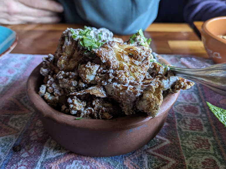 A bowl of fried food garnished with herbs on a dining table.
