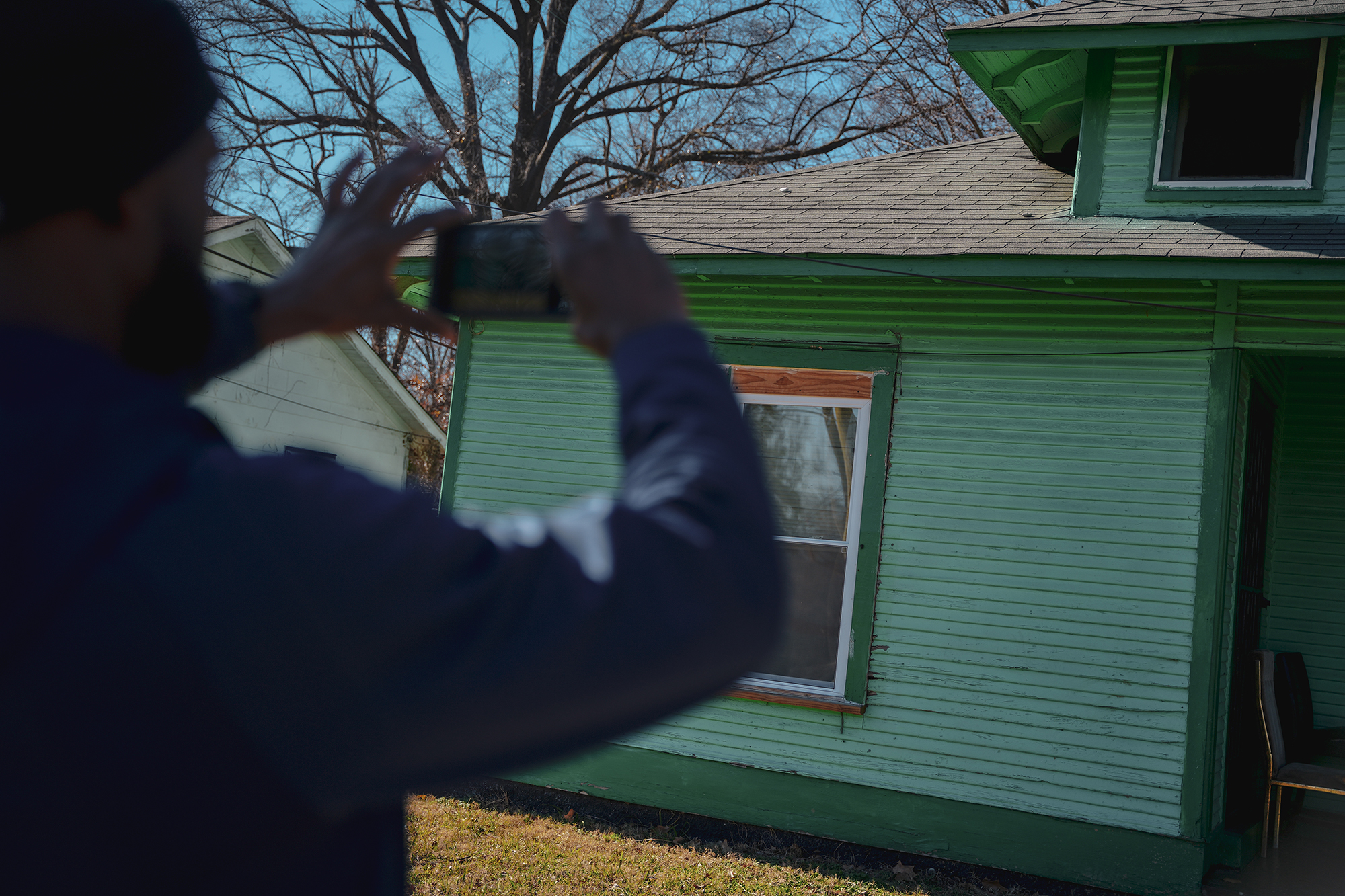 A person takes a photo of the outside of a green house. 