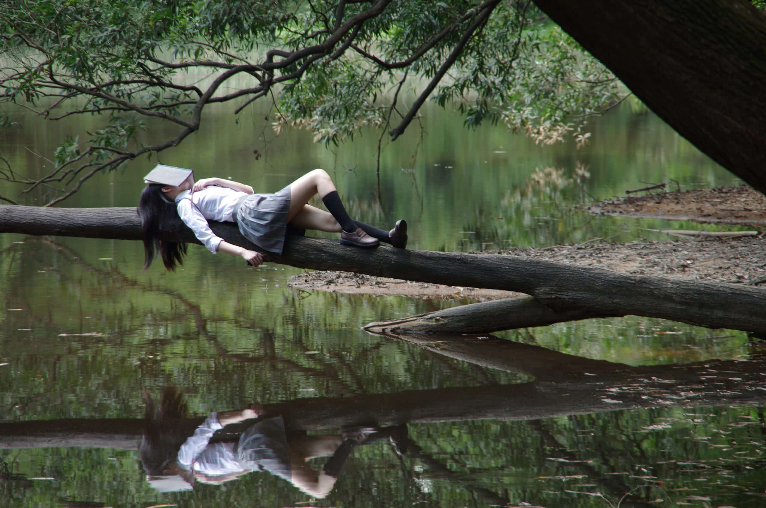 Girl napping on a tree branch on river