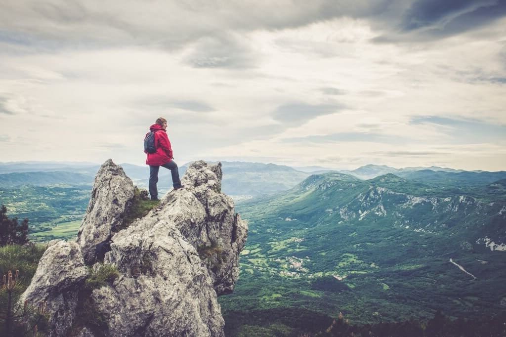 High achiever standing on the peak of a hill