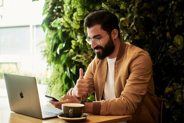 Man wearing brown shirt looking at his laptop and cellphone-anxiety about new job
