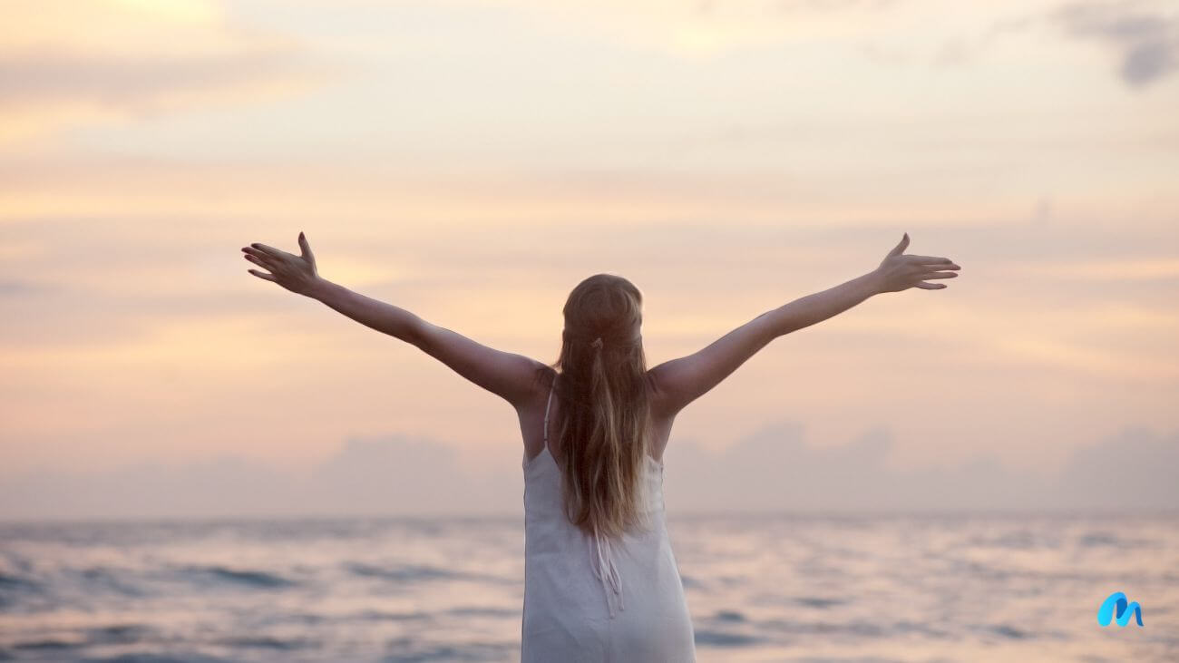 Lady stretching her arms during sunset at a beach-what it means to live your best life