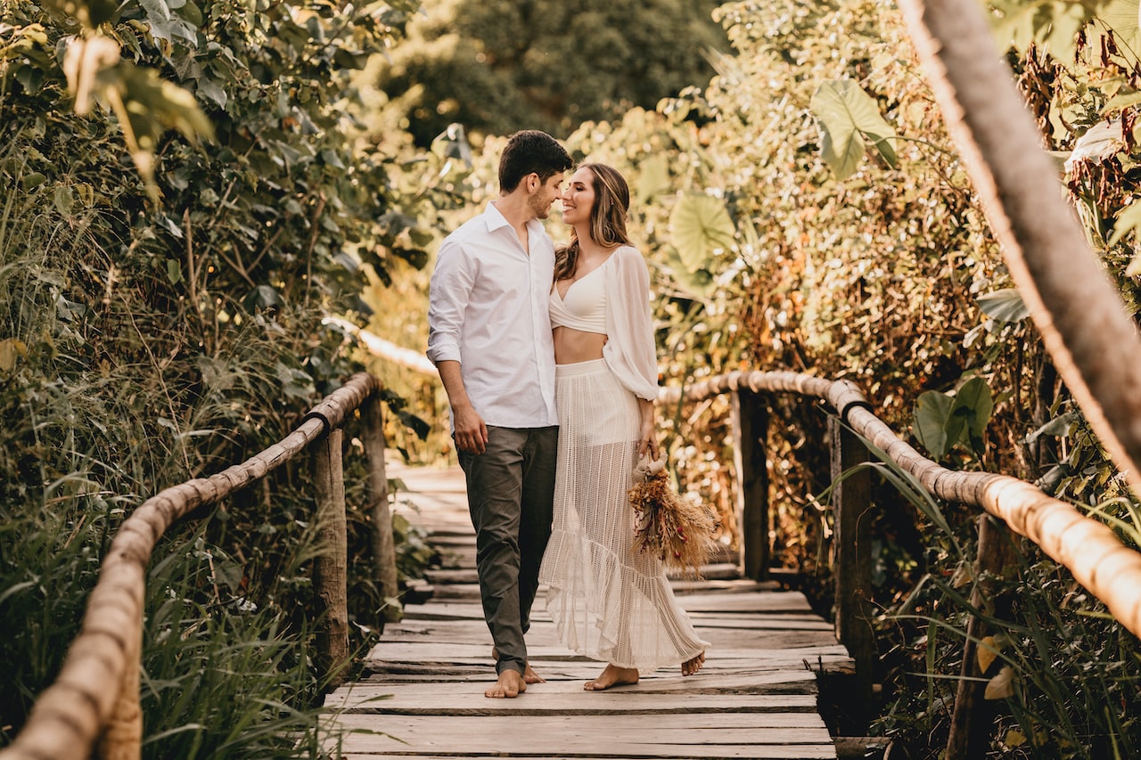 Man and woman walking on wooden bridge during daytime