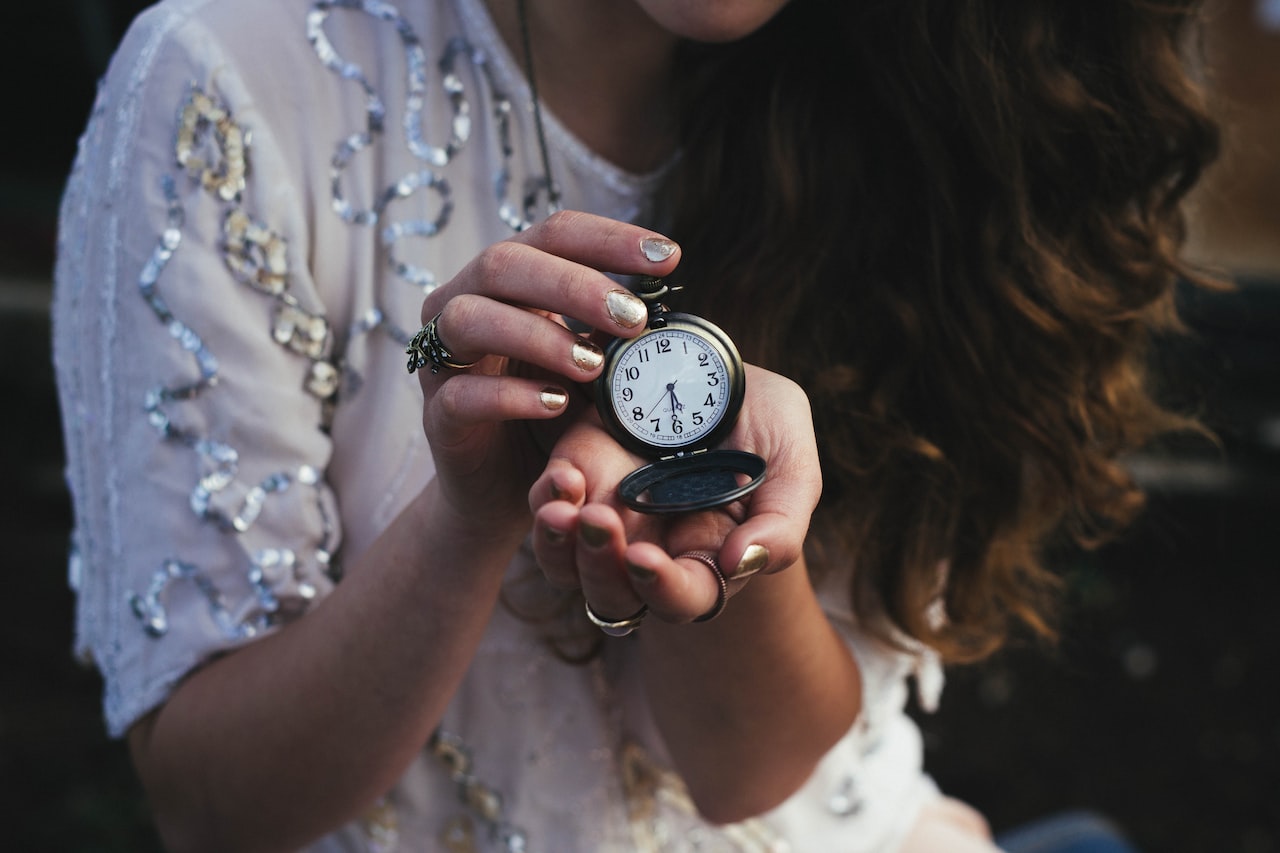 Woman holding black pocket watch at 5:30-no more waiting, its time