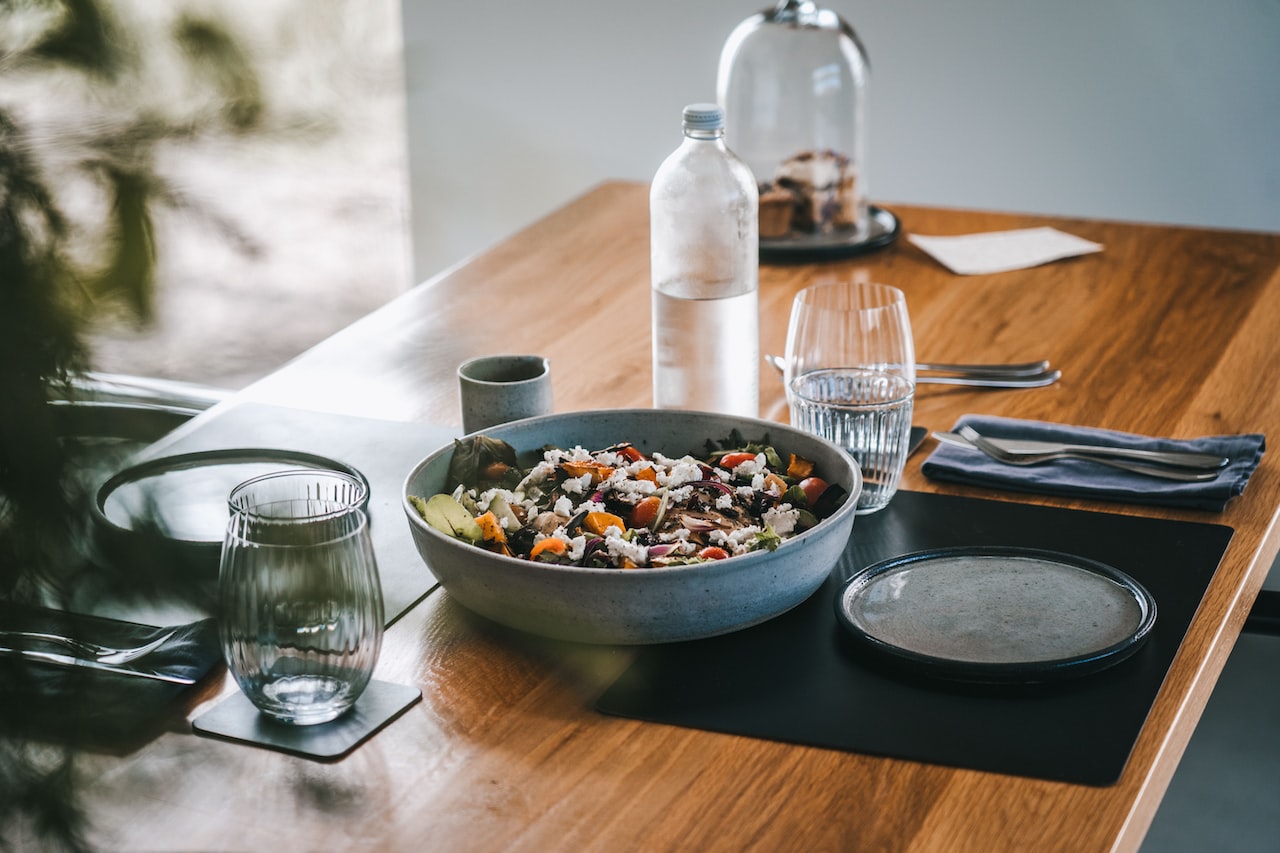 A wooden table topped with a bowl of food-cereal with water