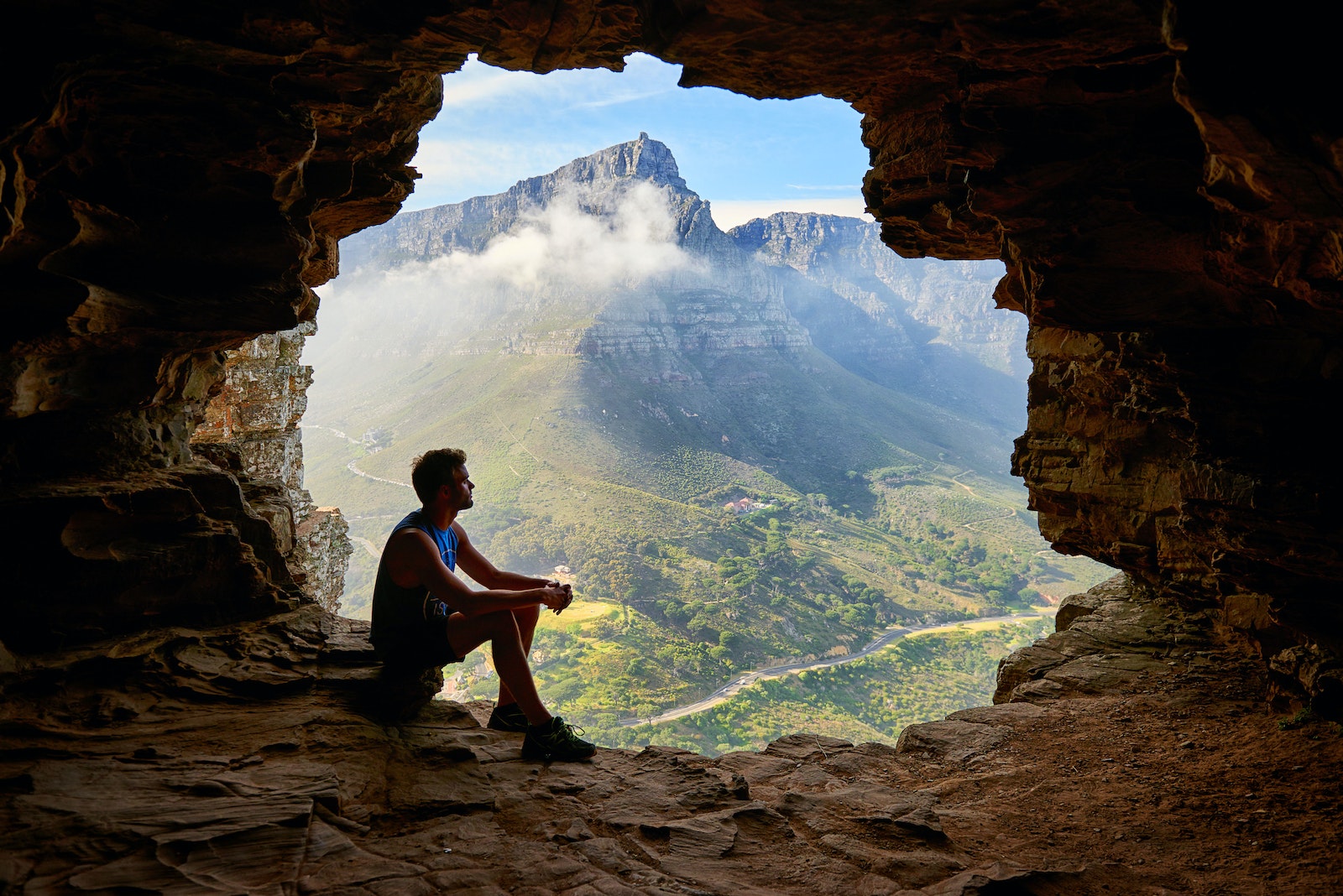 Photo of man sitting on a cave -the world owes you nothing