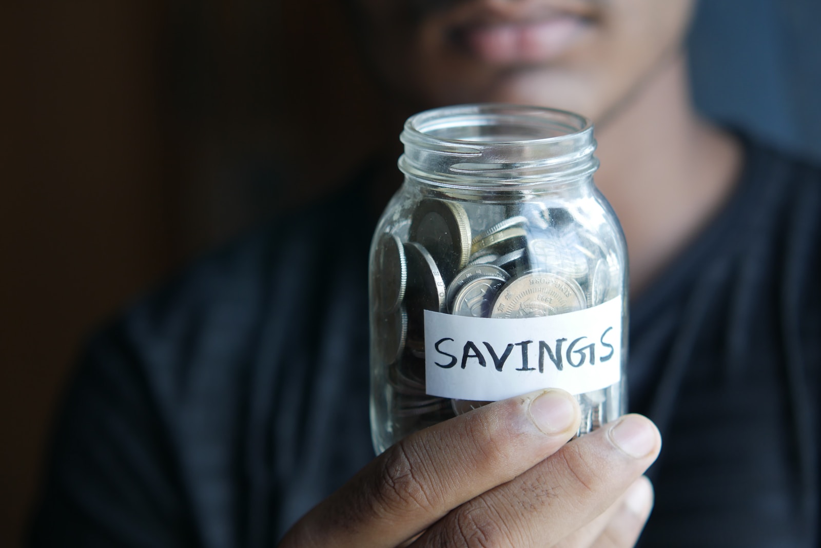 A man holding a jar with a savings label on it-budgeting for kids
