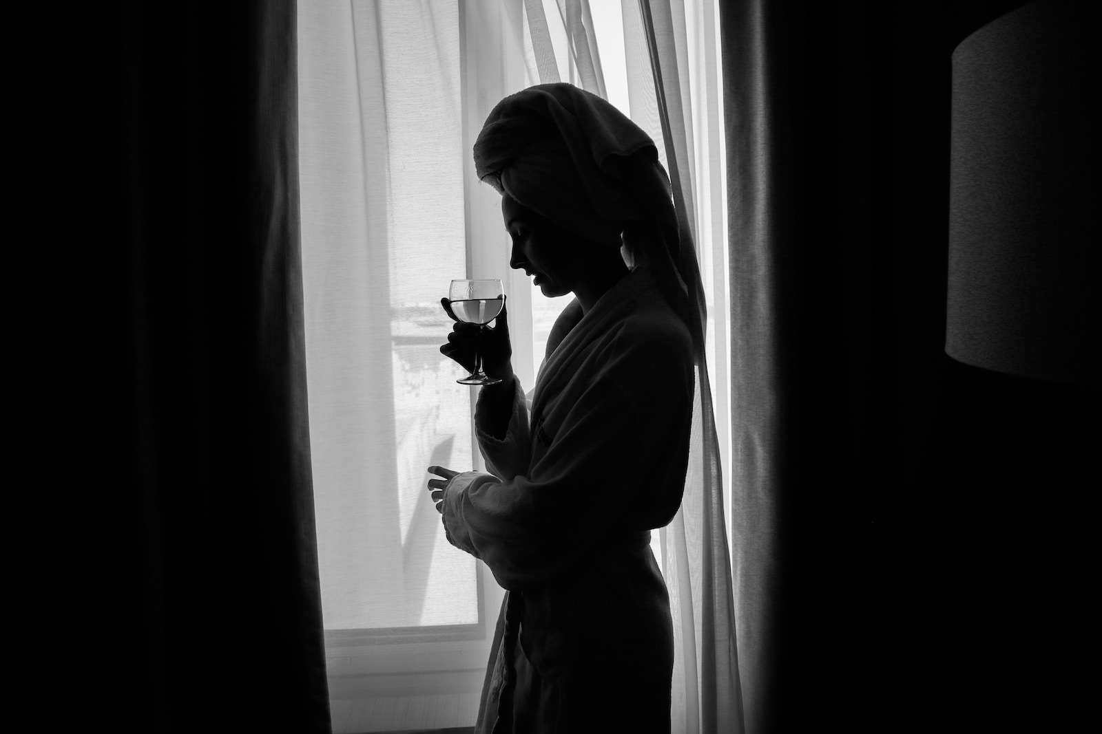A woman standing in front of a window holding a glass of wine-dangers of toxic self-care