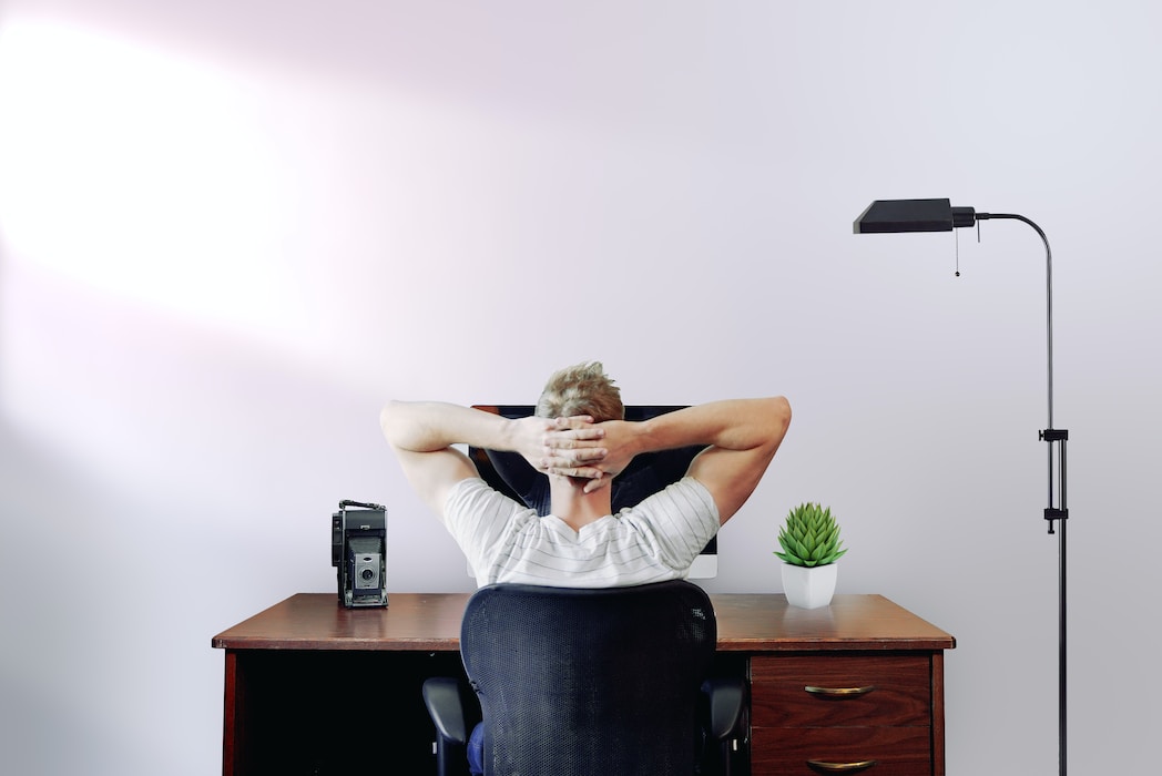 Man holding his head while sitting on chair near computer desk-i hate working from home