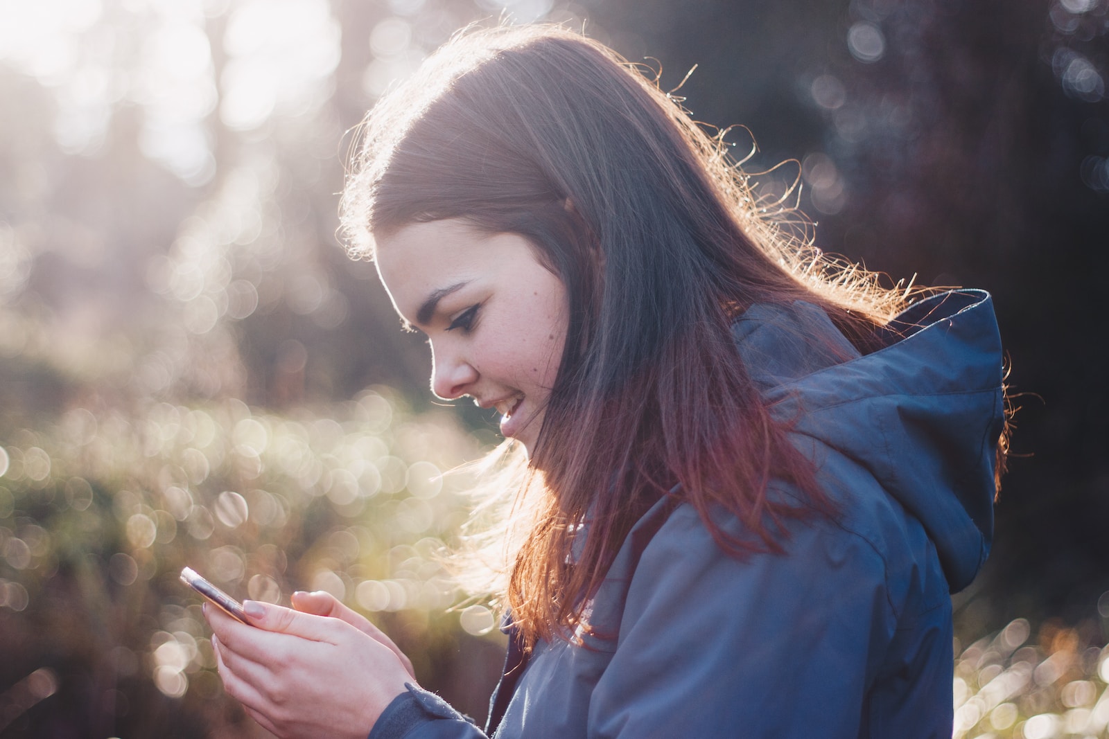 Woman holding phone smiling-should a 9 year-old have a phone