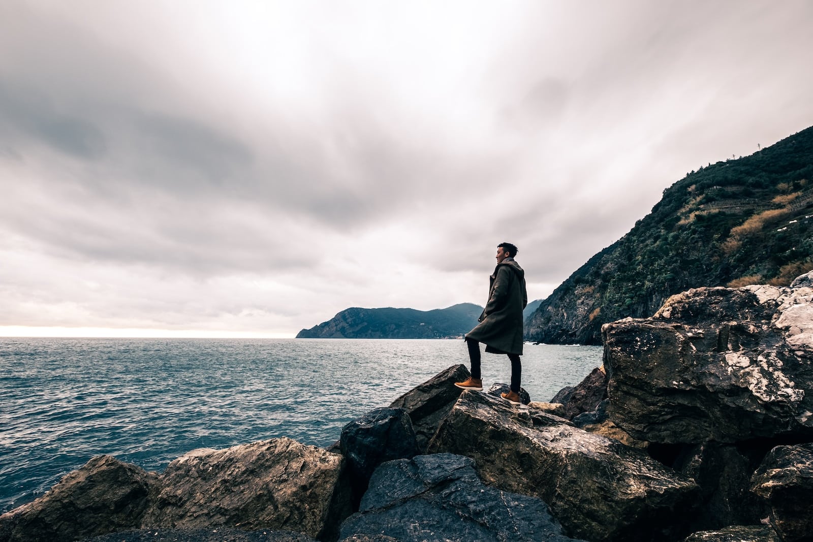 Man standing on boulder near body of water-ambitious person